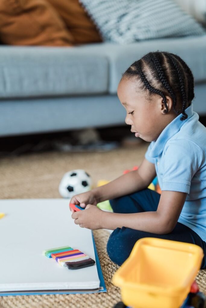 The Art of Drawing Readers In: Your attractive post title goes here African American child playing with colorful plasticine on floor indoors, promoting creativity.
