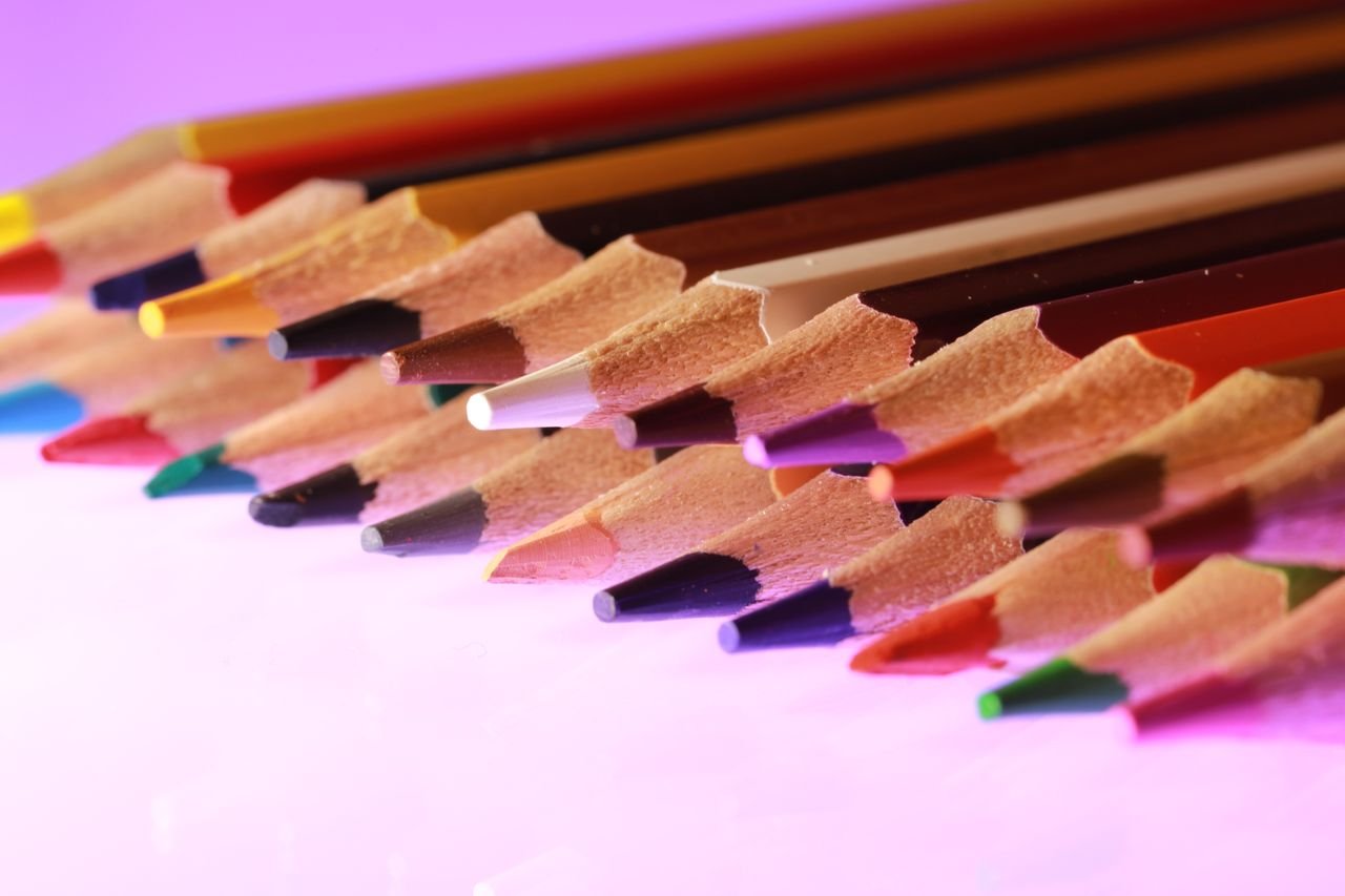 E-Shop Vibrant colored pencils aligned on a purple surface, showcasing creativity and artistic tools.