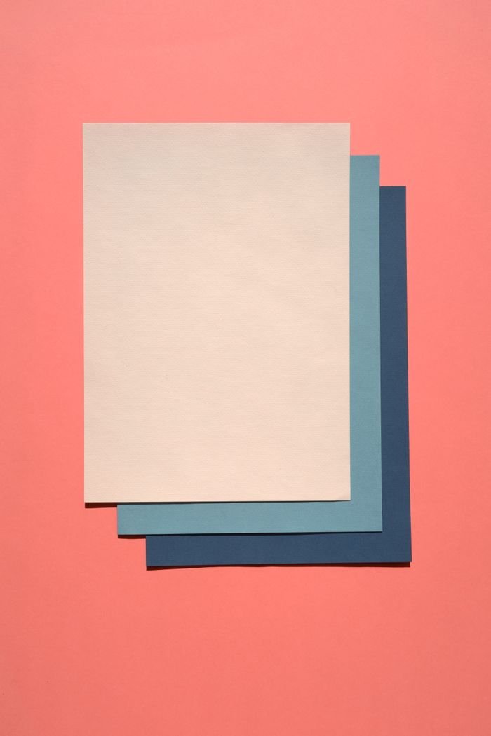 Close-up of vibrant colored papers layered on a pastel pink background.