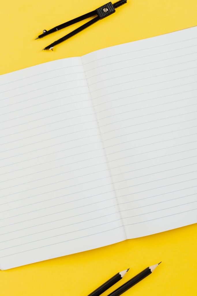 Crafting Captivating Headlines: Your awesome post title goes here Open lined notebook with pencils and compass on a bright yellow background. Ideal for educational themes.